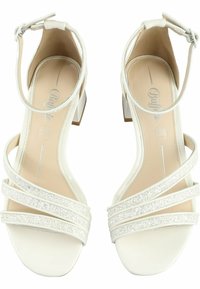 White patent leather sandals with three glittery straps, open toe design, square block heel, and adjustable ankle strap.