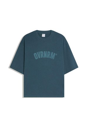 Ciemnoturkusowy, luźny T-shirt z krótkim rękawem i okrągłym dekoltem, z nadrukiem "OVRNRM" w pasującym kolorze na wysokości klatki piersiowej.