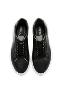 Baskets en cuir noir avec une texture lisse, dotées de semelles en caoutchouc blanches, de lacets noirs et d'accents gris sur la languette et sur les côtés.