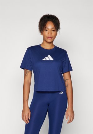 Crop top de sport à manches courtes bleu marine en tissu lisse avec un logo Adidas blanc. Associé à des leggings ajustés assortis.