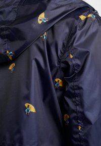 Navy blue fabric with a repeating pattern of small birds holding yellow umbrellas.