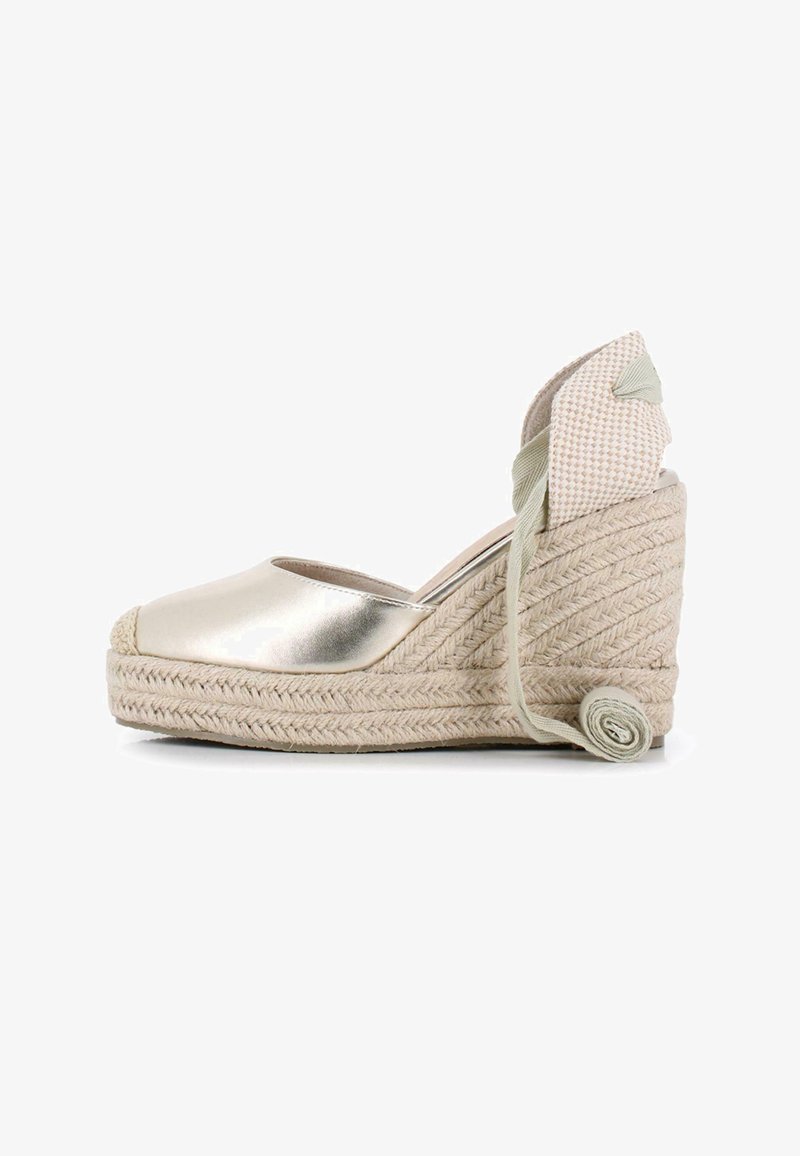 Espadrille de cuña metálica dorada con suela de yute trenzado, que presenta una parte trasera de lona y un detalle de lazada con un acento de cinta enrollada.