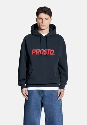Granatowa bluza z kapturem wykonana z mieszanki bawełny, z przednią kieszenią typu kangur. Posiada duże czerwone logo "PROSTO." na klatce piersiowej oraz sznurek przy kapturze.
