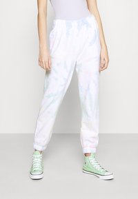 Pantalones jogger con estampado de corbata blanca y colores pasteles; cinturilla y puños elásticos; combinados con zapatillas altas en verde menta.
