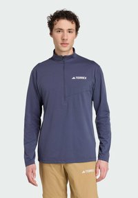 Námornícka dlhá rukávová košeľa s polovičným zipsom, obsahujúca vrecko na ľavej strane hrudníka a biele logo "TERREX", vyrobená z hladkej, ľahkej látky.