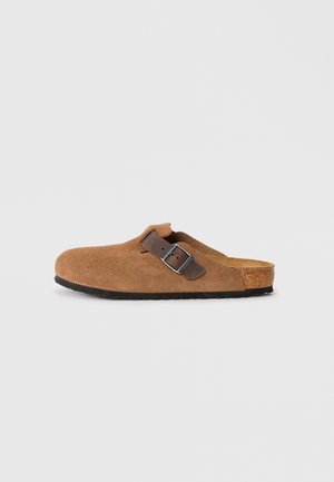 Brown suede clogs with a adjustable brown leather strap and silver buckle, featuring a molded cork footbed and textured rubber sole.