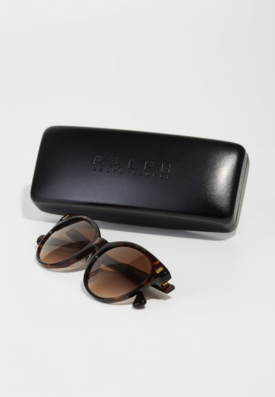 Schildpatt-Sonnenbrille mit braunen Verlaufslinsen, goldenen Akzenten und einem mattschwarzen Brillenetui, das mit "RALPH" geprägt ist.