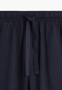 Granatowe dresy bawełniane z elastycznym paskiem w talii, wyposażone w teksturowany sznurek do regulacji i gładkie, miękkie wykończenie materiału.