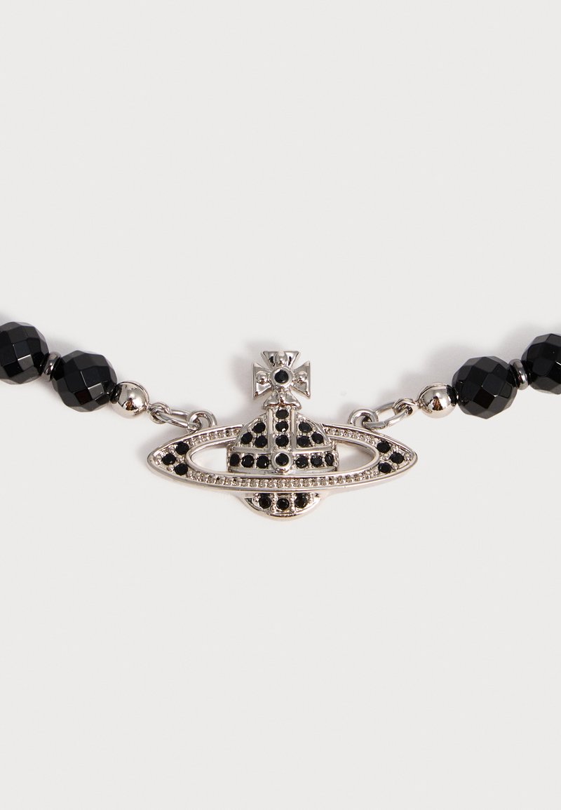 Pendentif sphérique ton argent avec pierres noires et détail croix, relié à un collier de perles noires facettées et petites perles argentées.