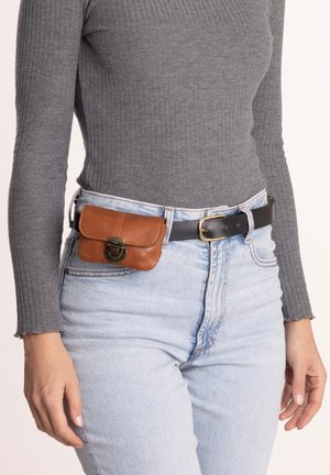 Pochette en cuir marron avec une fermeture à pince, attachée à une ceinture noire. Portée avec un jean taille haute bleu clair et un haut gris à manches longues côtelées.