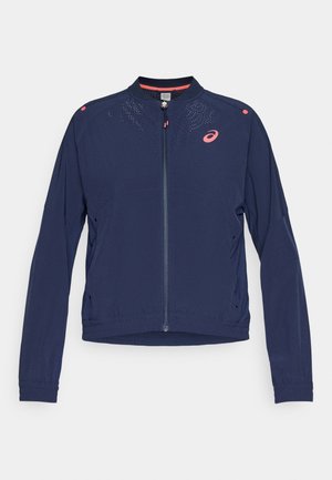 Veste légère marine à manches longues, fermeture éclair, accents texturés aux épaules et détails de conception perforés dans une couleur contrastante.