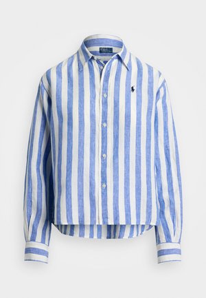Camisa de linho às riscas azuis e brancas, com colarinho, botões à frente e um pequeno logótipo bordado no peito. Mangas longas com detalhes nos punhos.