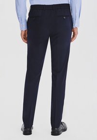 Granatowe spodnie z elastycznym paskiem w talii, z dwoma tylnymi kieszeniami i dopasowanym krojem. Gładki, lekki materiał o minimalnym połysku.