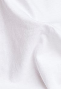 Tissu en coton blanc avec une texture lisse, présentant des plis subtils et un tissage doux et respirant. Convient à diverses applications vestimentaires.