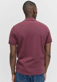 Burgundy kortärmad polo med klassisk krage, gjord av bomull. Har en enfärgad design och standard passform.