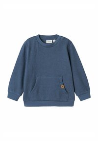 Felpa blu a costine con maniche lunghe, scollo rotondo e una tasca frontale. Presenta un piccolo etichetta marrone sulla tasca. Tessuto morbido.