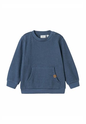 Felpa blu a costine con maniche lunghe, scollo rotondo e una tasca frontale. Presenta un piccolo etichetta marrone sulla tasca. Tessuto morbido.