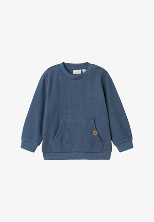 Felpa blu a costine con maniche lunghe, scollo rotondo e una tasca frontale. Presenta un piccolo etichetta marrone sulla tasca. Tessuto morbido.