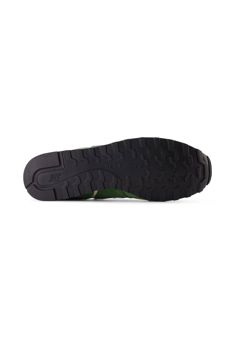 Schwarze Gummisohle mit strukturierten Mustern und einem oberen Teil aus grünem Wildleder und Mesh mit beigefarbenen Akzenten. Das "new balance"-Logo ist auf der Sohle geprägt.