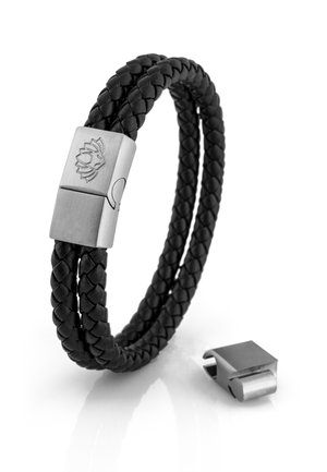 Bracelet en cuir tressé noir avec un fermoir en métal de couleur argentée présentant un design gravé. Le fermoir est séparé du bracelet.