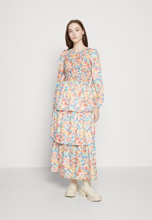 Φoρεμα μακρι ε με φλοράλ εκτύπωση σε πορτοκαλί, μπλε και πράσινο; διαθέτει καμωμένη σιλουέτα, μακριά φουσκωτά μανίκια και φούστα με επίπεδα. Συνδυασμένο με μπεζ χοντρά μποτάκια.
