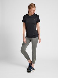 Svart kortärmad träningsskjorta i strukturerad tyg, matchad med grå leggings med en figurnära design och en liten logotypdetalj. Svarta sneakers.