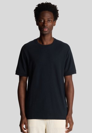 T-shirt in cotone nero con maniche corte, colletto rotondo e vestibilità rilassata. Tessuto morbido, cuciture minime e senza motivi o dettagli visibili.