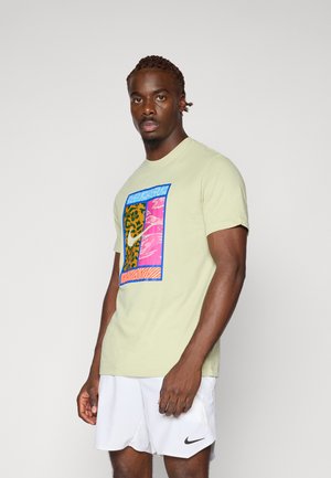 Hellgrünes Baumwoll-T-Shirt mit einem mehrfarbigen Grafikdesign, das Leopardenmuster sowie rosa und blaue Akzente zeigt. Kurze Ärmel und Rundhalsausschnitt.