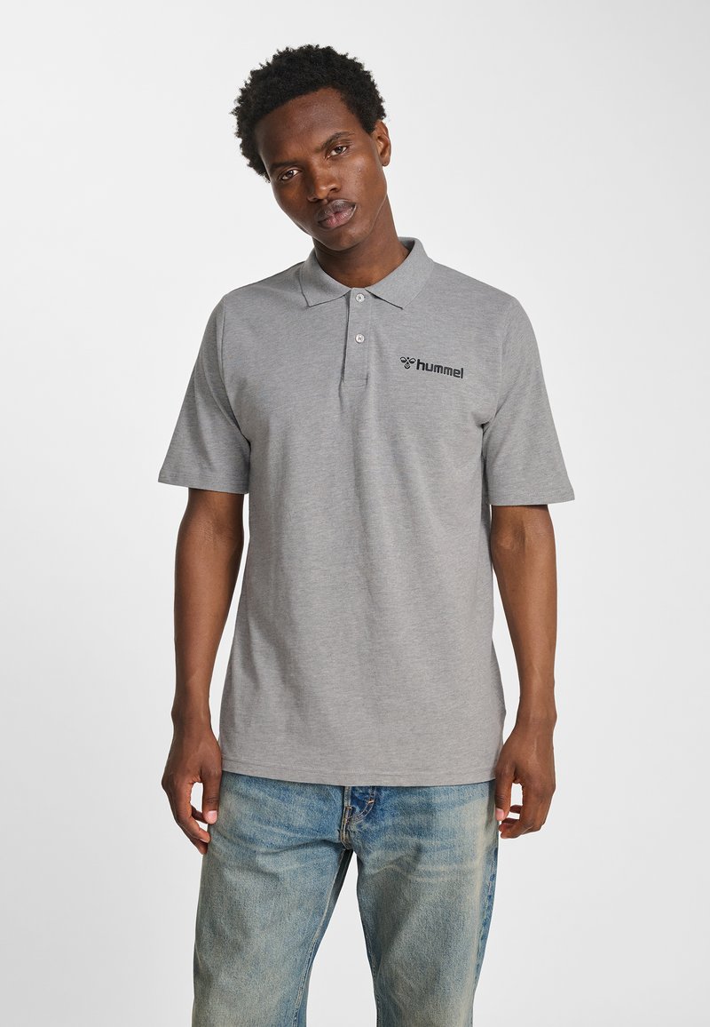 Szara koszulka polo z bawełny, z kołnierzykiem, krótkimi rękawami i subtelnym logo na lewej piersi. Połączona z niebieskimi jeansami.