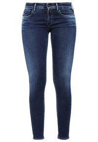 Jeans ajustados de mezclilla azul oscuro con un diseño clásico de cinco bolsillos, que cuentan con un cierre de botón y cremallera, y un ligero desgastado en la parte frontal.