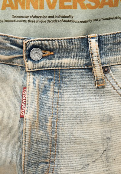 Svijetlosivi traperice s istaknutim detaljima, narančastim šavovima, metalnim zatvaranjem i crvenom DSQUARED2 etiketom na prednjem džepu.