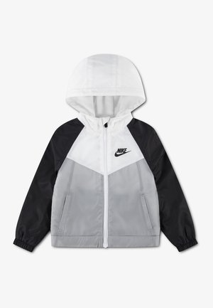 Hupparillinen tuulenpitävä takki mustilla hihoilla, valkoinen yläosa rinnassa, harmaa alaosa edessä, edessä vetoketju, sivutaskut ja Nike-logo rinnassa.