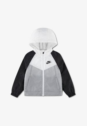 Hupparillinen tuulenpitävä takki mustilla hihoilla, valkoinen yläosa rinnassa, harmaa alaosa edessä, edessä vetoketju, sivutaskut ja Nike-logo rinnassa.