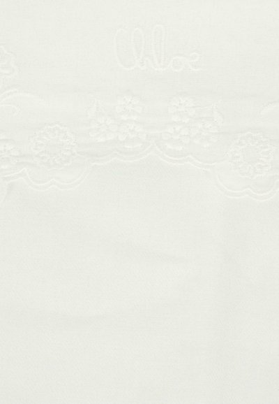 Tissu en coton blanc avec une bordure brodée en forme de vagues présentant des motifs floraux. Logo "Chloé" subtil en fil clair au-dessus du design.