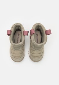 Botas aislantes beige con textura acolchada, tirantes rosas y suelas acolchadas. Cuenta con una costura elevada y un forro suave en el interior.