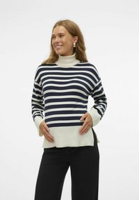 Suéter a rayas con un cuello alto. Presenta rayas horizontales en azul marino y crema, puños acanalados y un corte holgado con aberturas laterales.