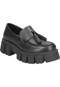 Mocassins en cuir noir avec une semelle en caoutchouc épaisse, présentant un design cousu, des pampilles décoratives et une texture lisse.