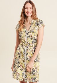 Kurzärmliges Kleid mit lebhaftem Blätterdruck in Gelb, Schwarz und Rot, mit Gürtel in der Taille und Taschen, hergestellt aus einem Stoff mit glatter Textur.