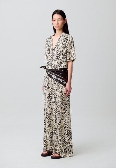 Vestido largo en color crema con estampado de leopardo negro, mangas cortas, escote en V, cintura ceñida con un cinturón estampado negro y sandalias planas.