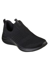 Zapatilla negra sin cordones con una parte superior de tejido transpirable, patrones texturizados y una suela de goma con un diseño de banda para mayor agarre.