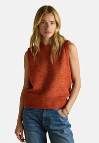 Varrukateta kootud sviiter rustoranzis, millel on kalliskivimuster ja soonikkoeserv, koos siniste teksapükstega. Sujuv tekstuur ja mugav stiil.