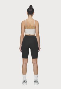 Se llevan juntos unos pantalones cortos de motorista de tiro alto de color negro y una camiseta corta blanca. La tela parece suave, ligera y ajustada.