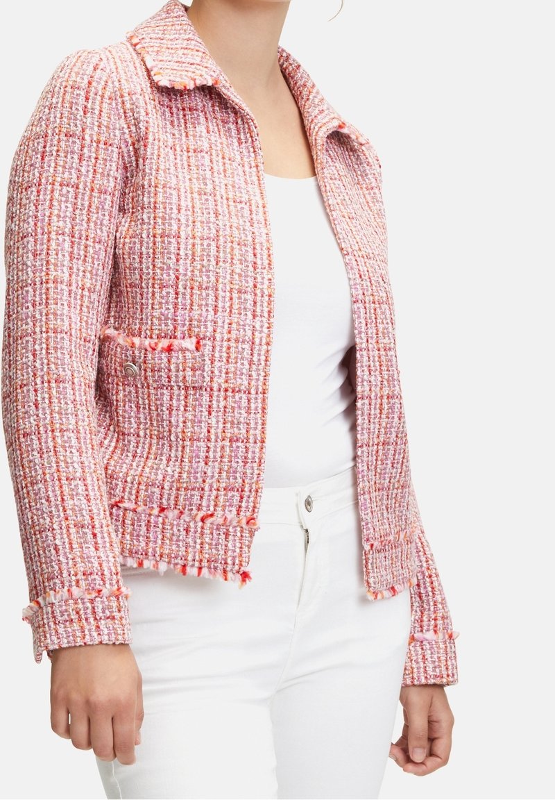 Różowa i biała tweedowa kurtka z kołnierzykiem, teksturowanym wykończeniem i frędzlami na brzegach. Posiada dwie przednie kieszenie oraz zapięcie na guziki.