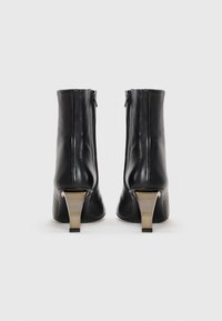 Black leather ankle boots with a smooth texture, zipper closure, and angular gold-tone heels. The design is modern with a sleek silhouette.