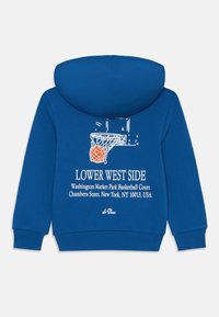 Zila kapuce džemperis, izgatavots no kokvilnas maisījuma, aizmugurē ir balta basketbola grafika un teksts, kas ietver atrašanās vietas informāciju.