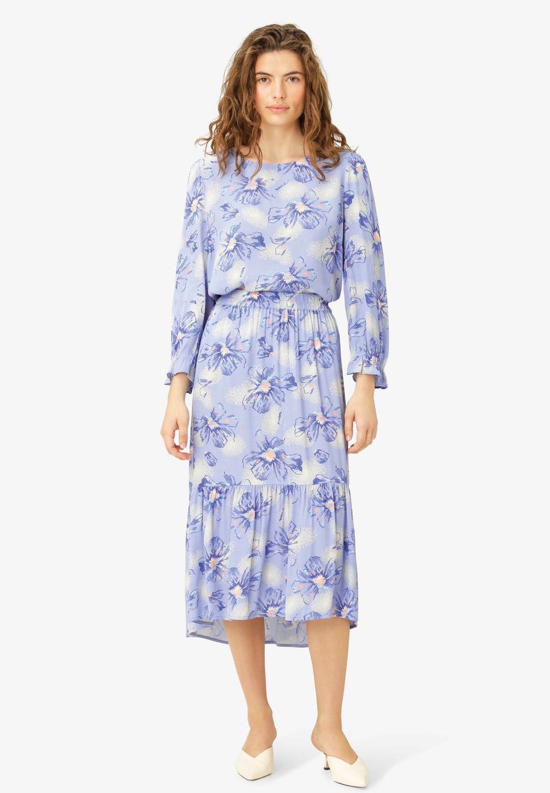 Rochie florală de culoare albastru deschis, cu talie elastică, mâneci lungi și fustă în straturi. Fabricată dintr-un material moale, cu modele de flori violet și roz.