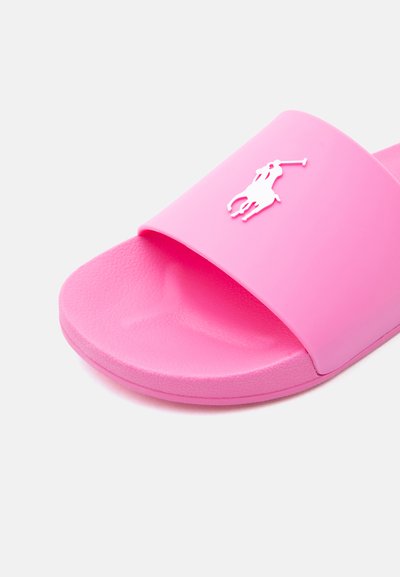 Ροζ σαγιονάρα από καουτσούκ με φαρδιά λουρί και λευκό ανάγλυφο λογότυπο παίκτη πόλο στο επάνω μέρος, υφασμένο πέλμα για καλύτερη πρόσφυση και άνεση.