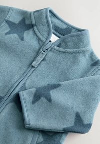 Giacca in felpa di un blu tenue con motivo a stelle. Caratterizzata da chiusura con zip, colletto alto e polsini a coste per una vestibilità aderente. Texture morbida.
