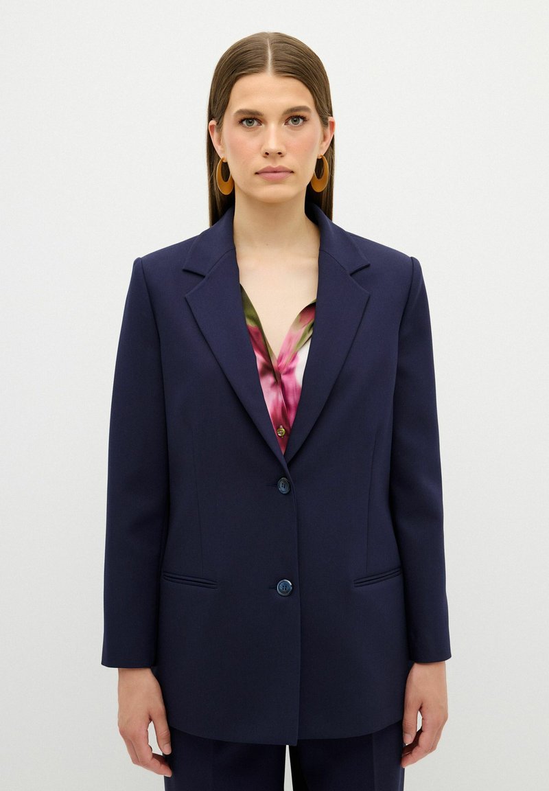 Námořnická blejzr s klopami, zavírání na jeden knoflík, dvě přední kapsy a texturovaná tkanina. Nosit na barevném blůze.