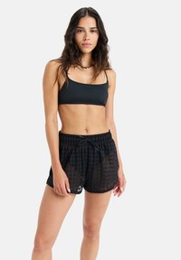 Black mesh shorts with a grid pattern and an elastic waistband. Paired with a solid black crop top.